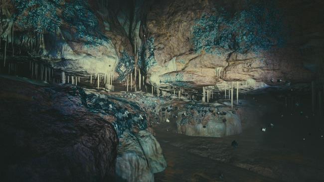 A dark cave with glowing and floating rocks, being lit by a flashlight.