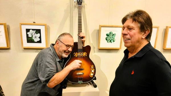 Bassist Mark Pfaff, left, and guitarist Warren Wolf couldn't keep their hands off the exhibits at a recent book launch party for Roger Fritz, subject of the new book "A Luthier's Life."