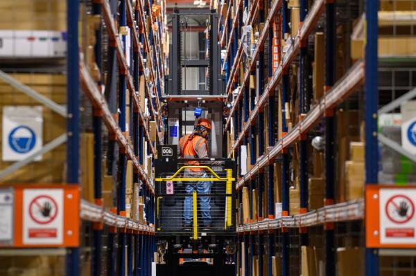 A worker uses a forklift truck to reach high shelves at the Amazon logistics centre in Sulzetal. 